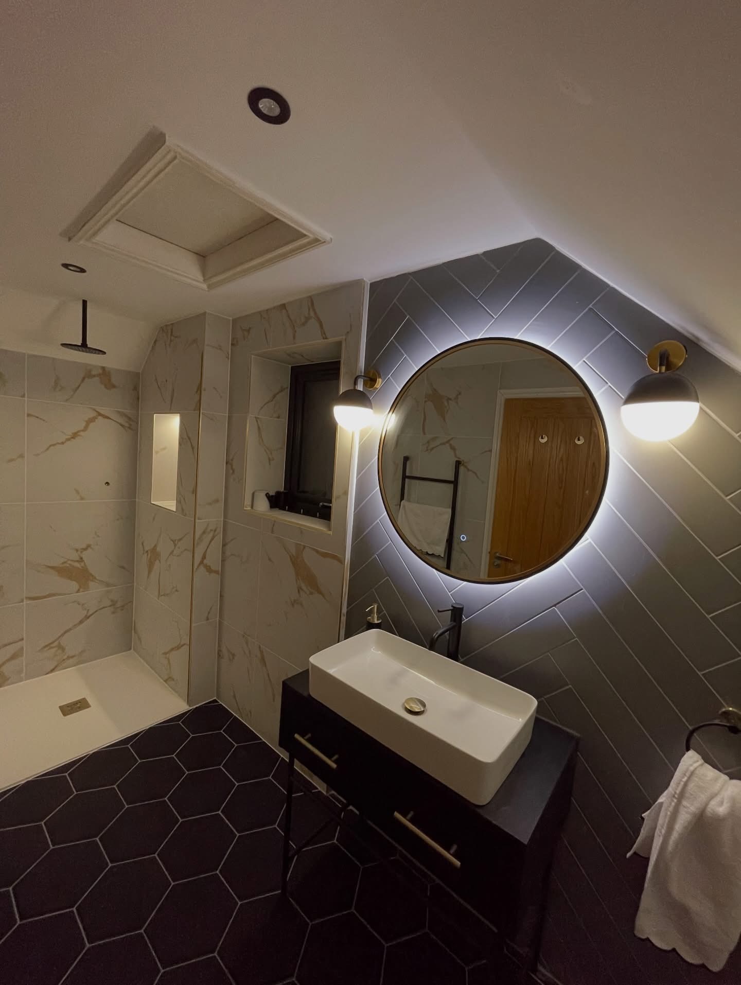 Bathroom installation with backlit round mirror, pendant wall lights and recessed downlights