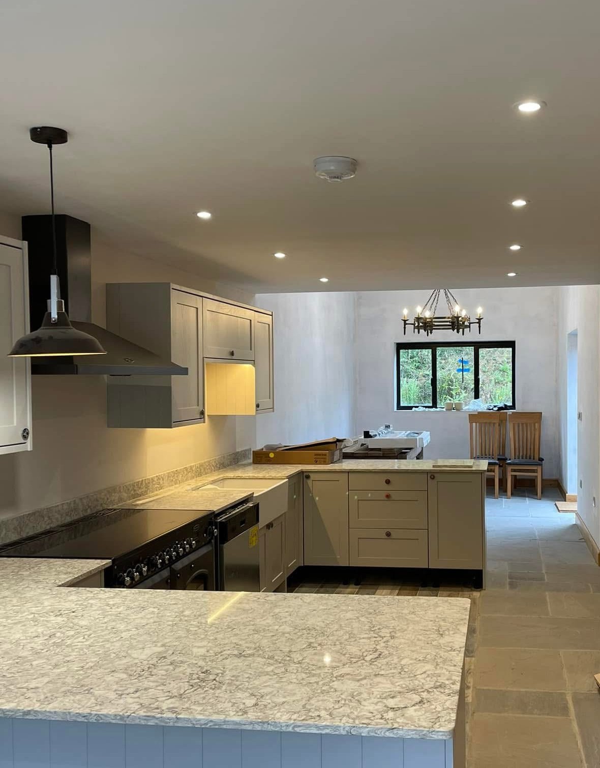 Completed kitchen installation with downlights, pendant lighting and marble-effect worktops