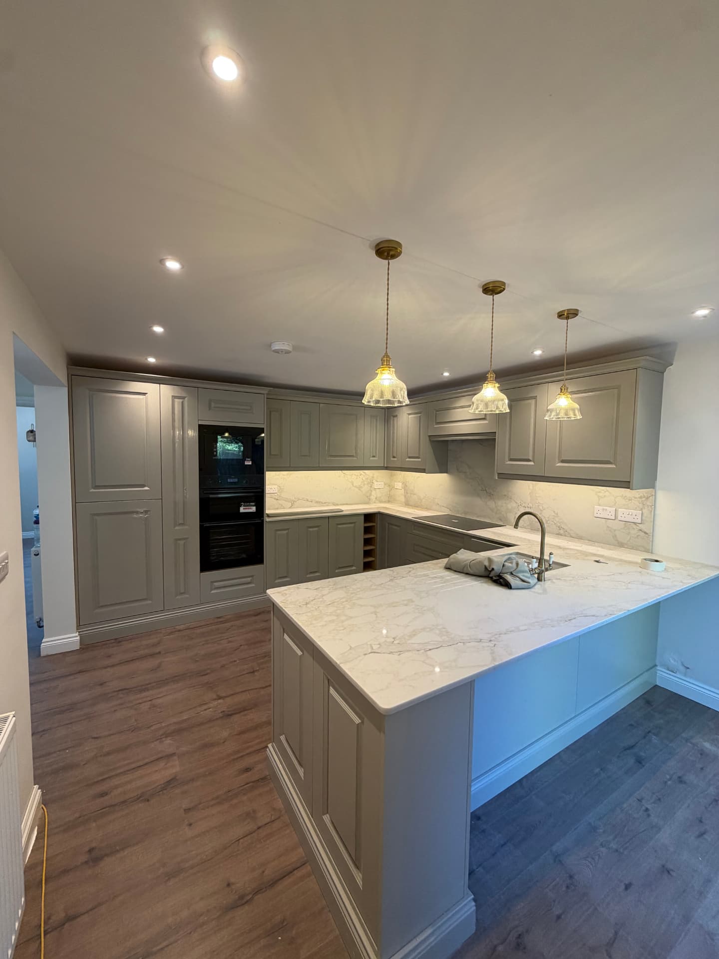 Finished kitchen installation with pendant lights and downlighting
